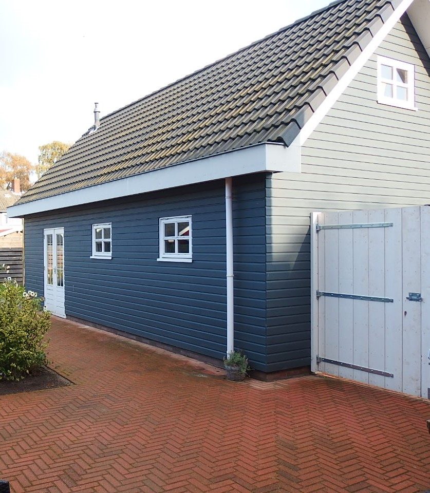 Klassiek uitgevoerd bouwproject met donkere houten gevelbekleding en witte kozijnen