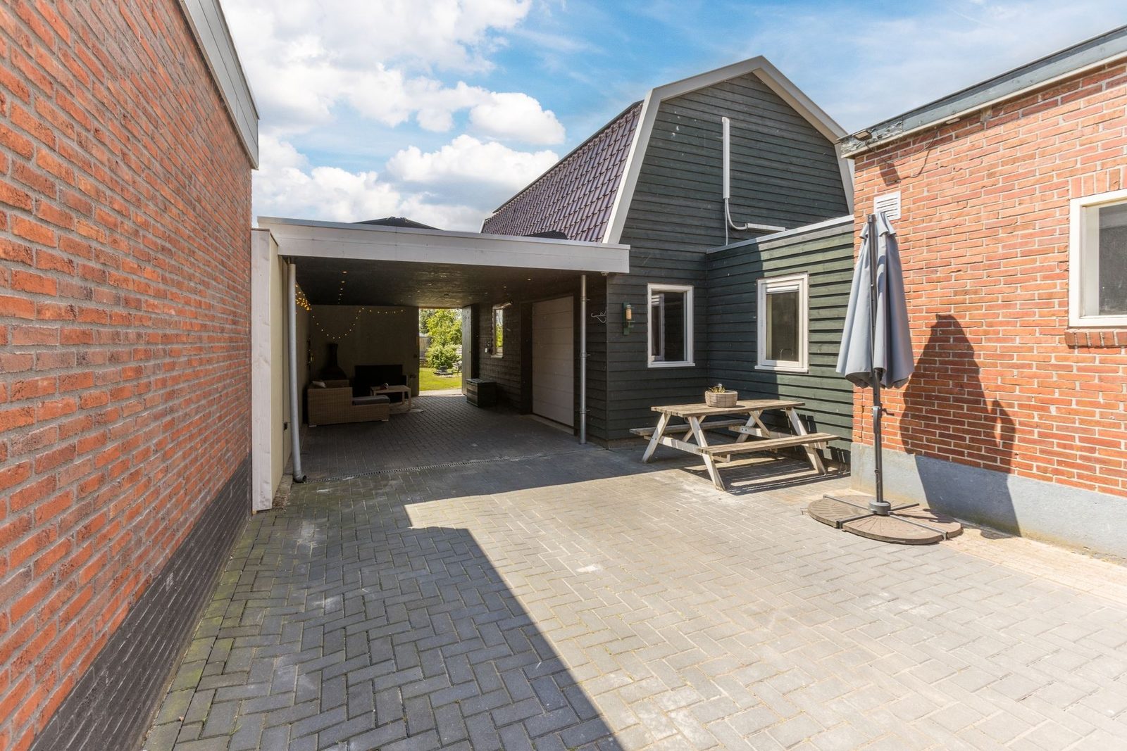 Houten schuur met aangebouwde overkapping tussen bestaande gebouwen